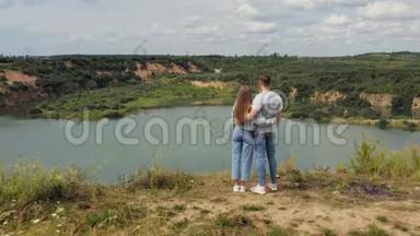 一对夫妇站在湖边的山崖上。 恋爱中的情侣在美丽景色的背景下拥抱